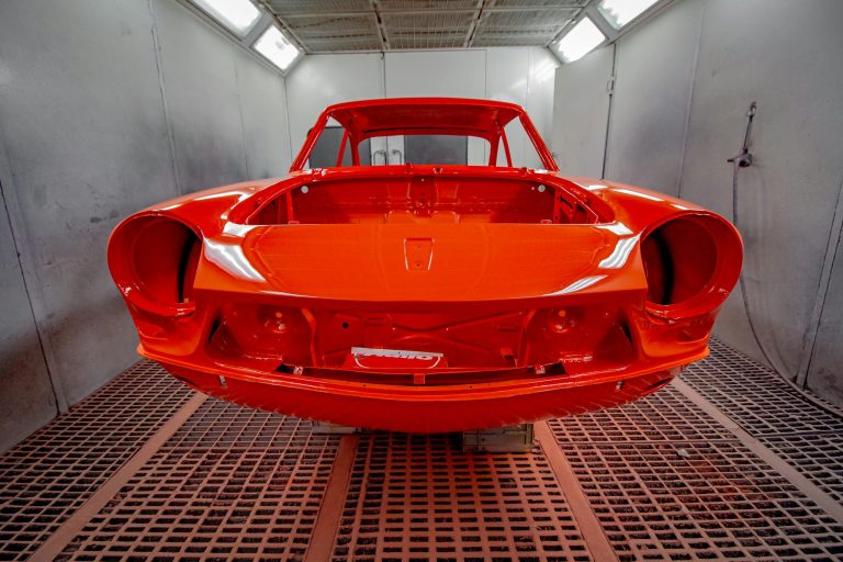 Vividly painted car body in a professional industrial spray paint booth.